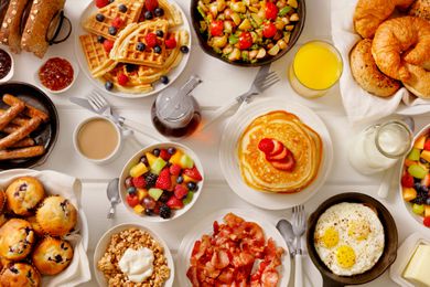 A variety of breakfast items including pancakes, waffles, fruit, eggs, and croissants