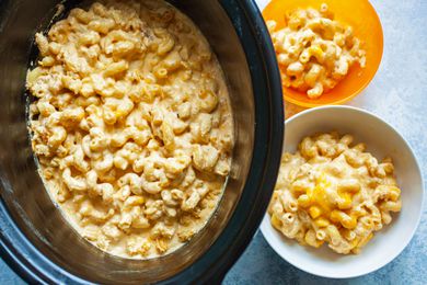 Slow cooker filled with mac and cheese and two plated portions alongside