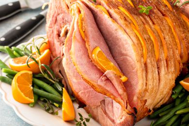 Spiral sliced glazed ham stuffed with orange slices and herbs
