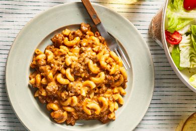 homemade hamburger helper on a plate next to a side salad