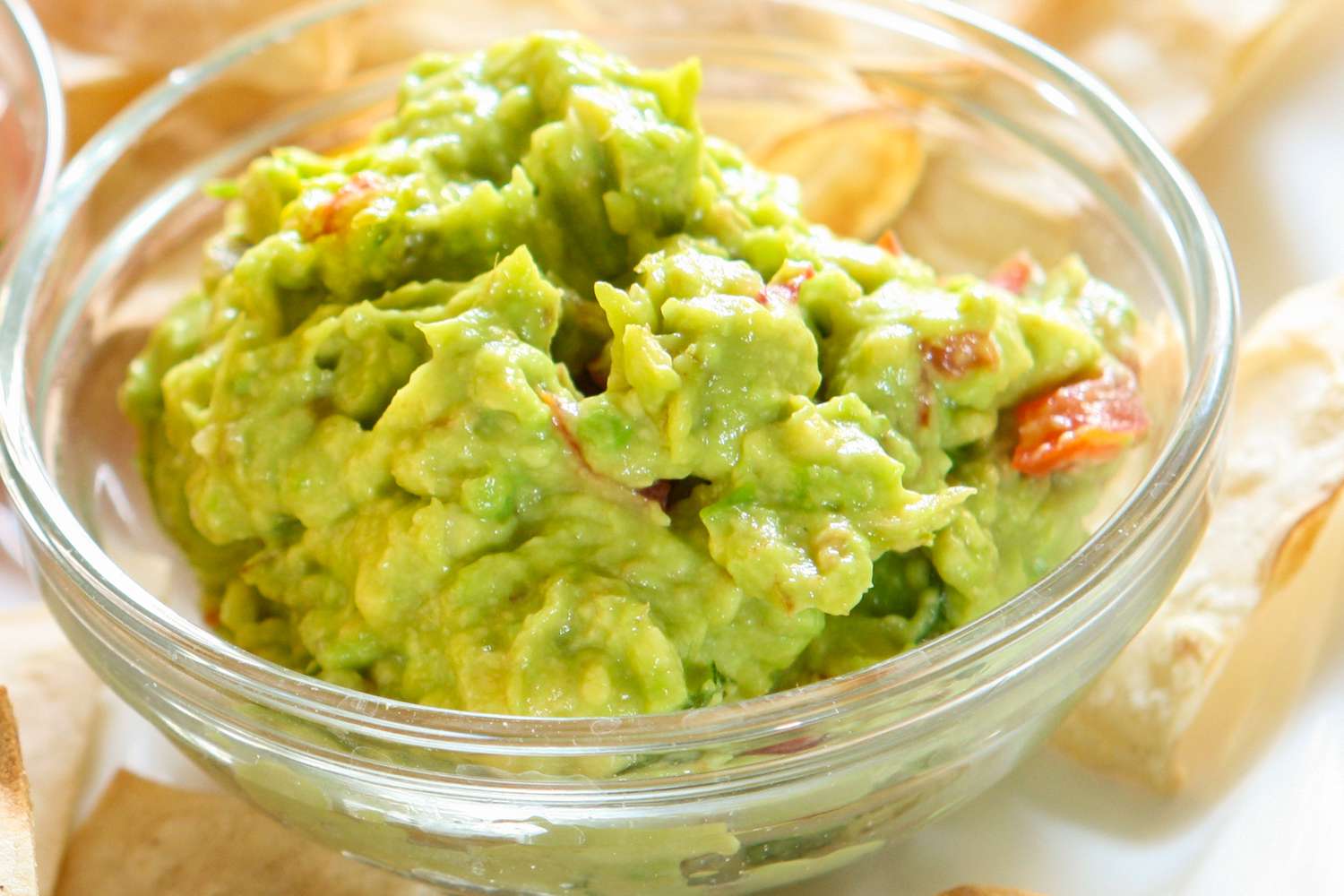 Bowl of guacamole with tortilla chips in the background