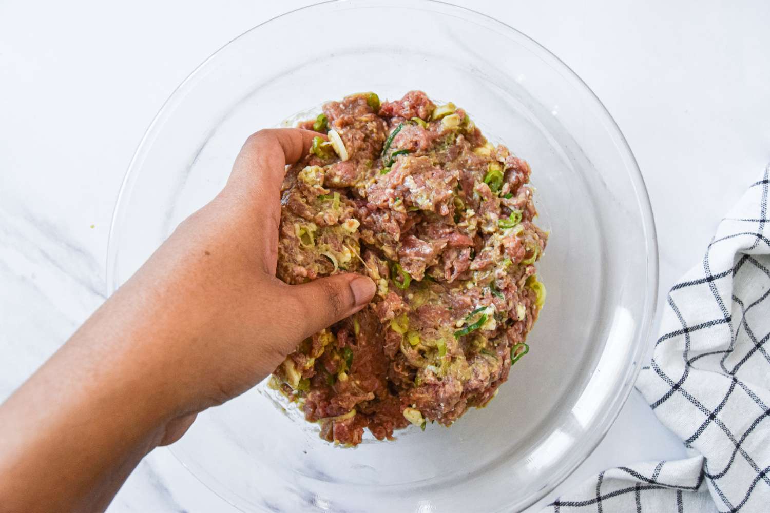 Hand Mixing Together Blue Cheese Burgers Ingredients (Ground Beef, Garlic, Green Onions, Blue Cheese, etc)
