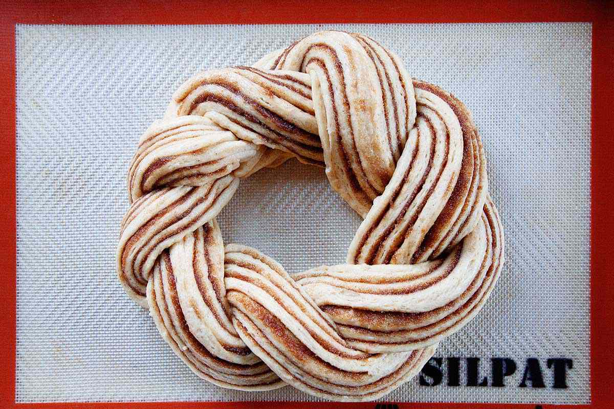 Homemade King Cake dough has risen and sitting on a baking sheet.