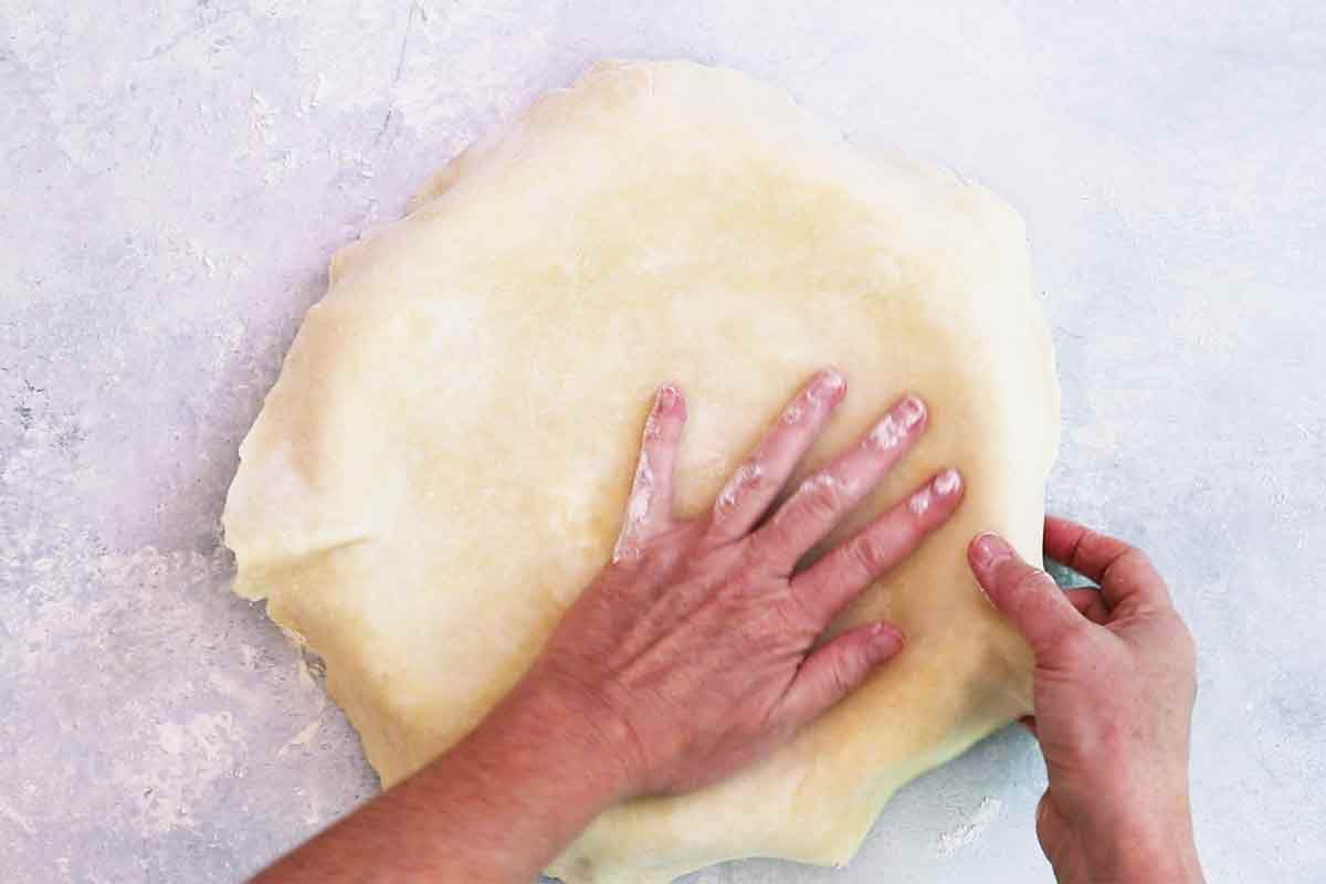 A pie crust being placed in a pie dish