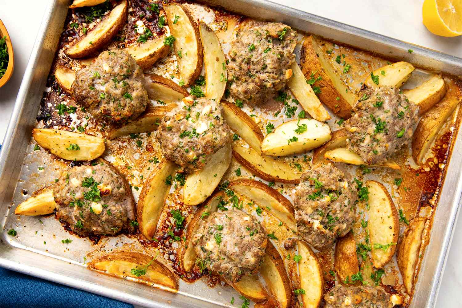 Baked meatballs with potato wedges on a tray