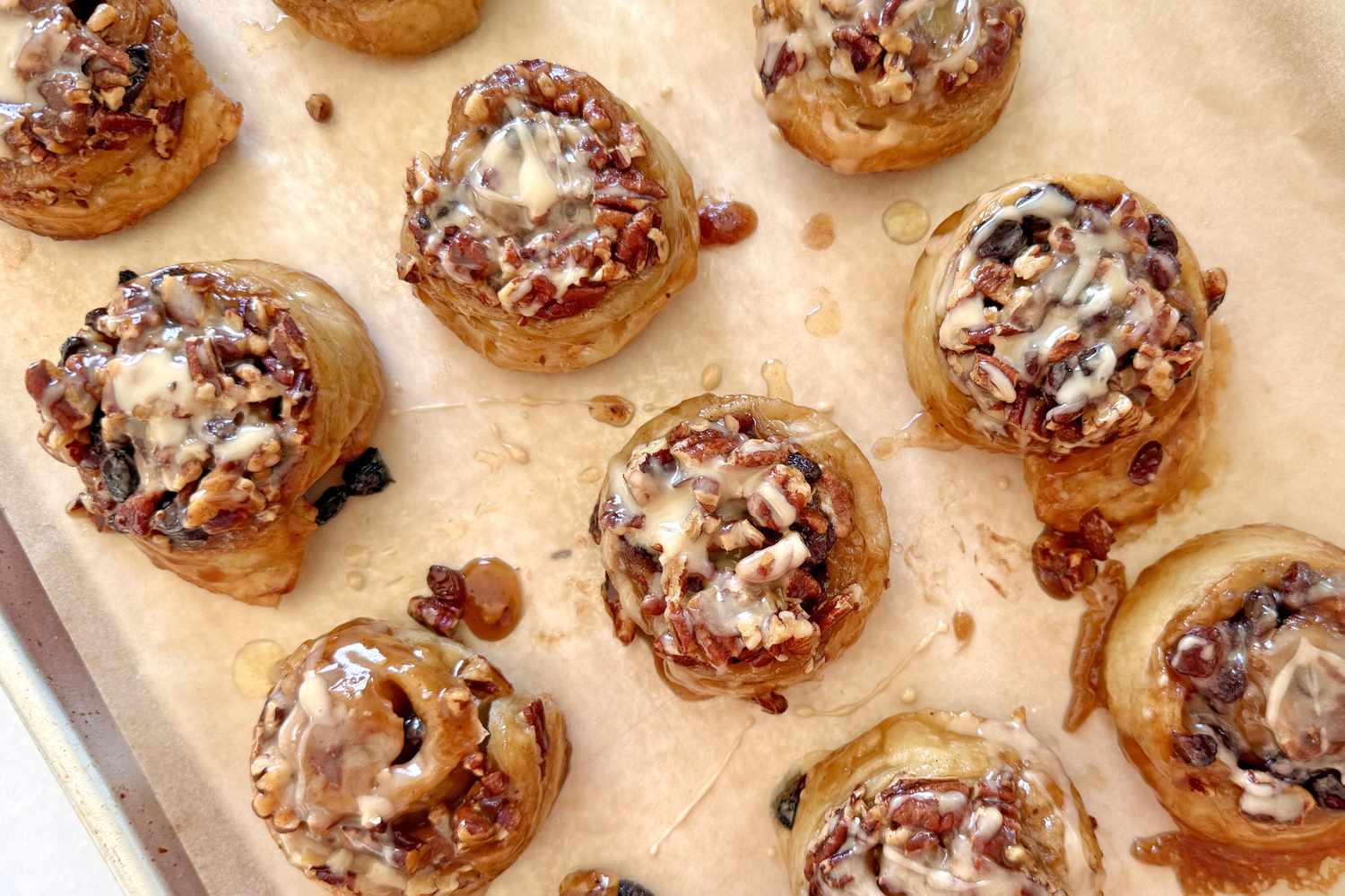 Tray of sticky buns topped with pecans and glaze displaying a baked dessert