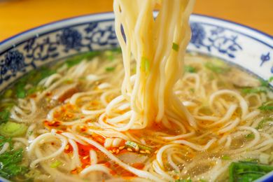 ramen noodles lifted from a bowl ramen with soup