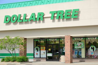 The exterior of a Dollar Tree retail store showing the green signage and entrance with promotional displays