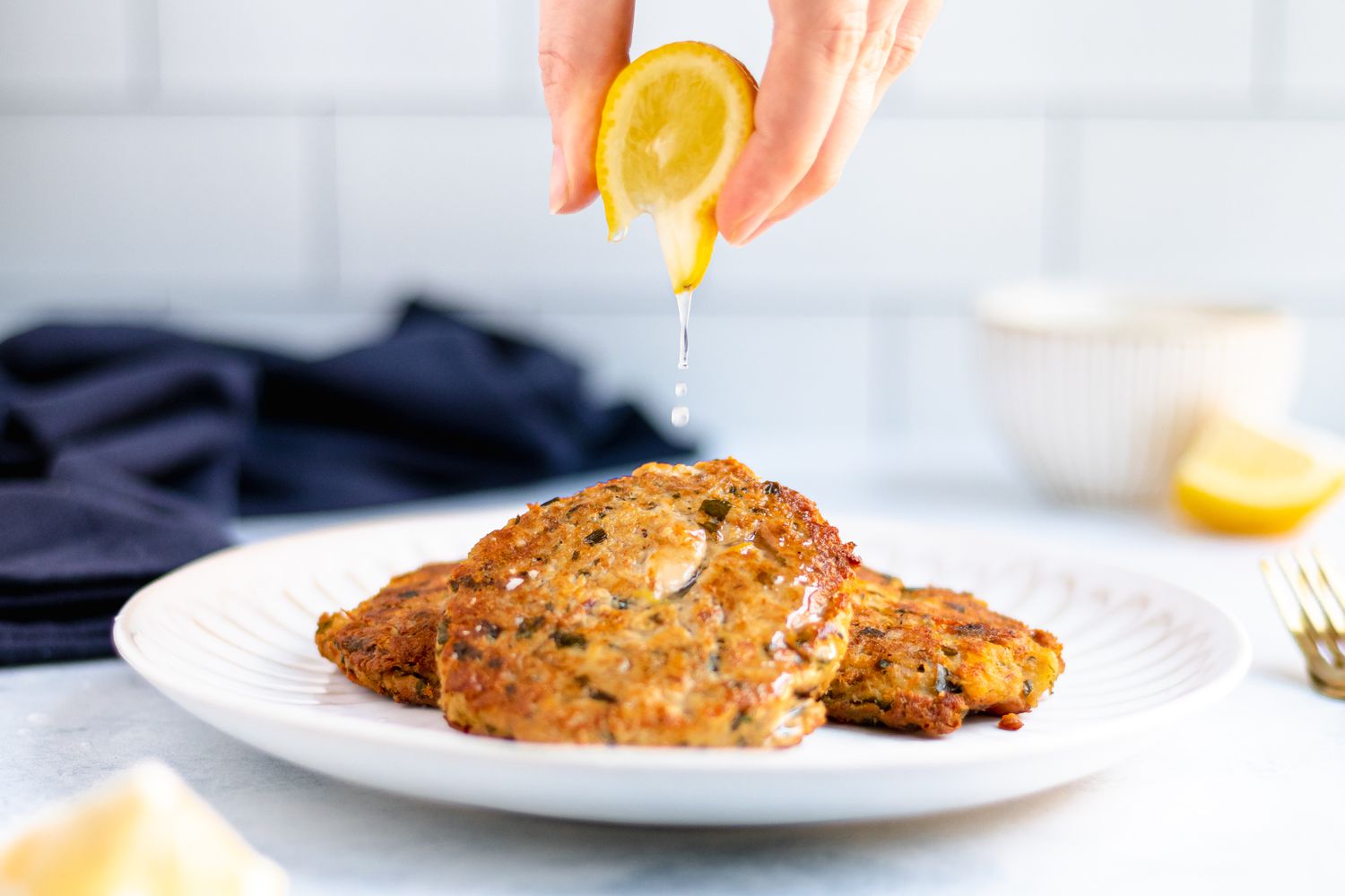 Squeezing lemon on tuna cakes.
