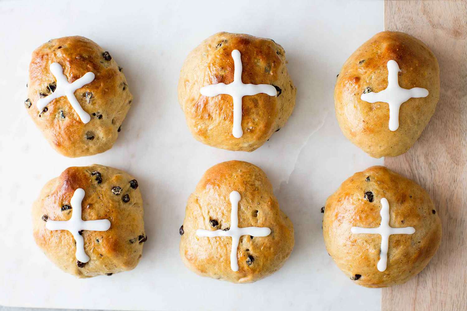 Homemade Hot Cross Buns on a surface with sugar crosses piped on top