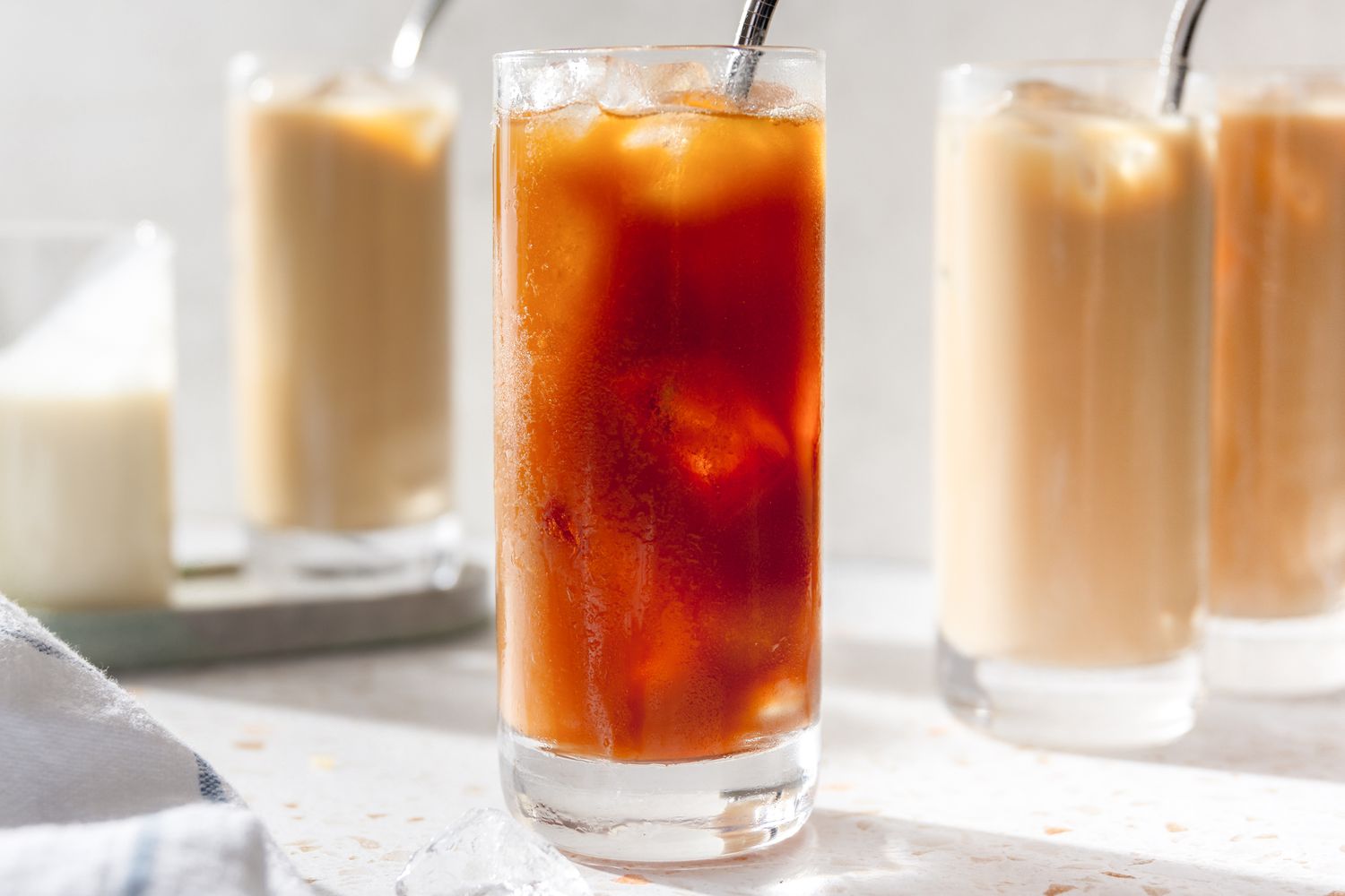 Glass of Thai Iced Tea (No Milk Added), and in the Background More Glasses of Thai Ice Tea (With Milk Added)