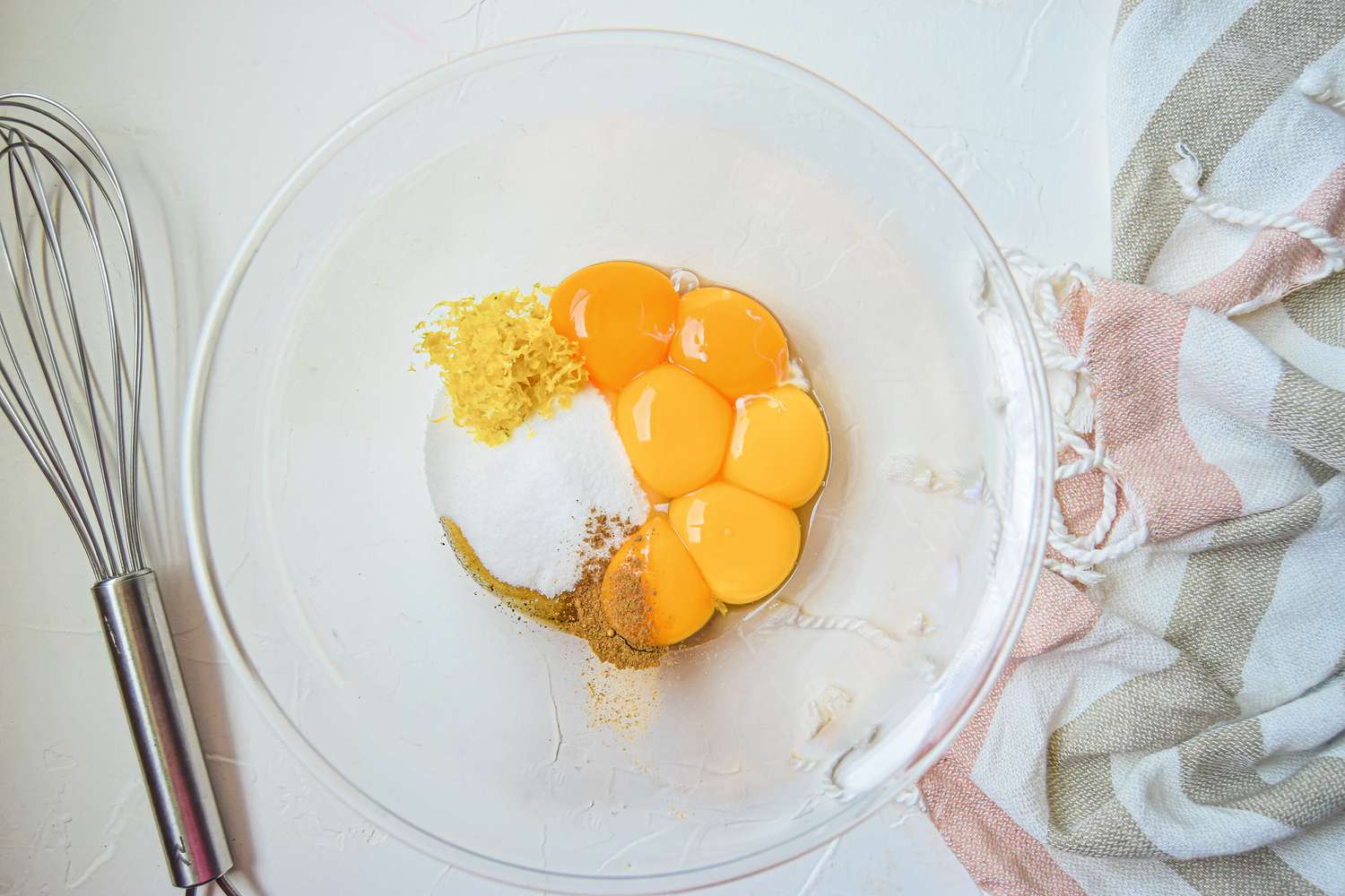 A glass bowl with egg yolks and ingredients for a abaglione recipe.