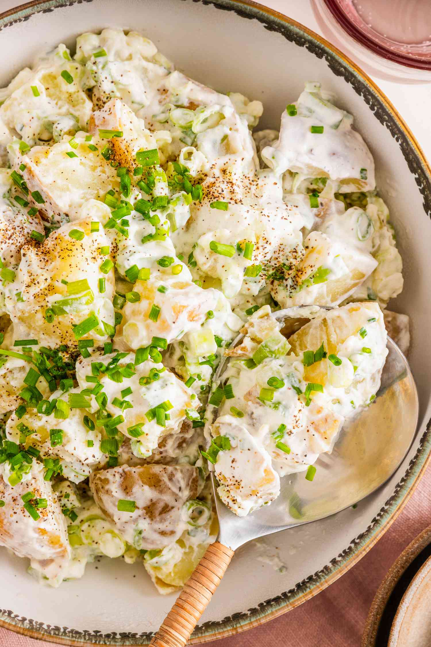 Bowl of Sour Cream and Onion Potato Salad With a Serving Spoon