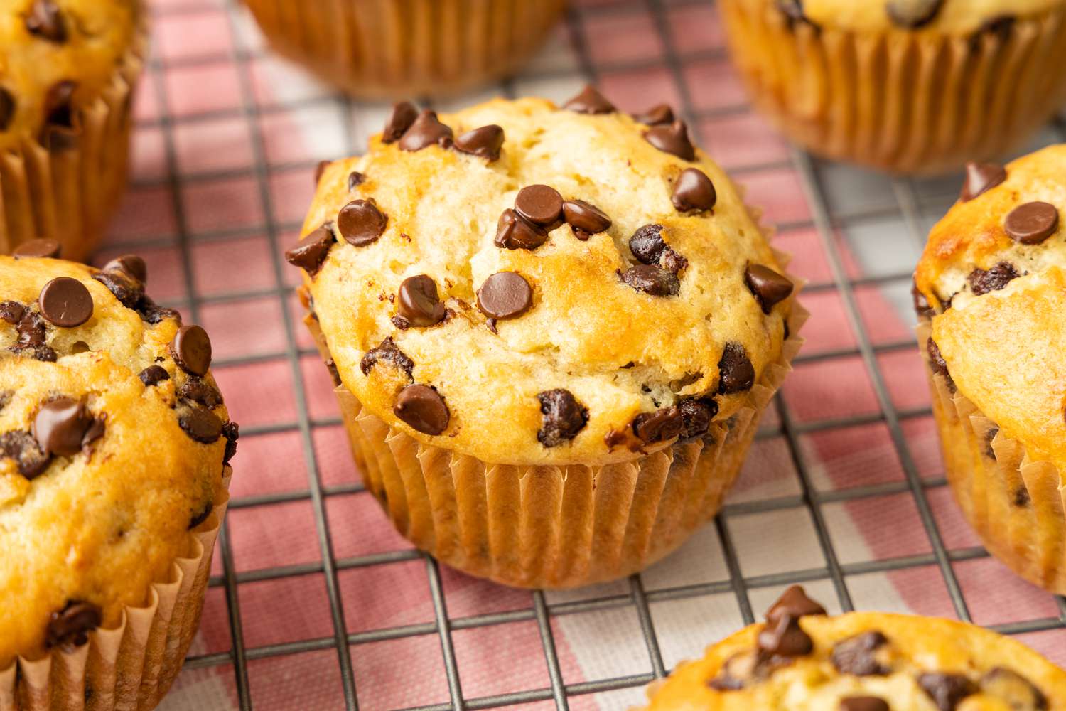 Banana Chocolate Chip Muffins on a Cooling Rack Over a Kitchen Towel
