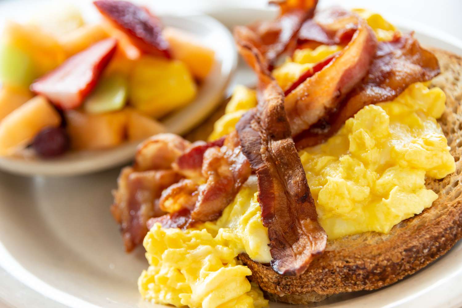 toast topped with scrambled eggs and bacon