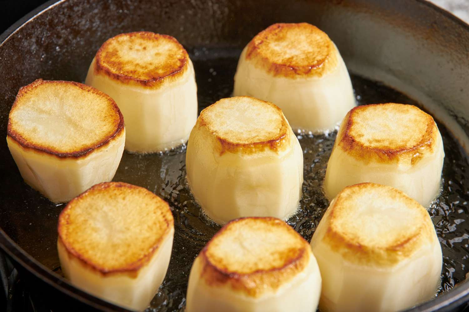 Potatoes flipped and the other side seared on the skillet for fondant potatoes recipe