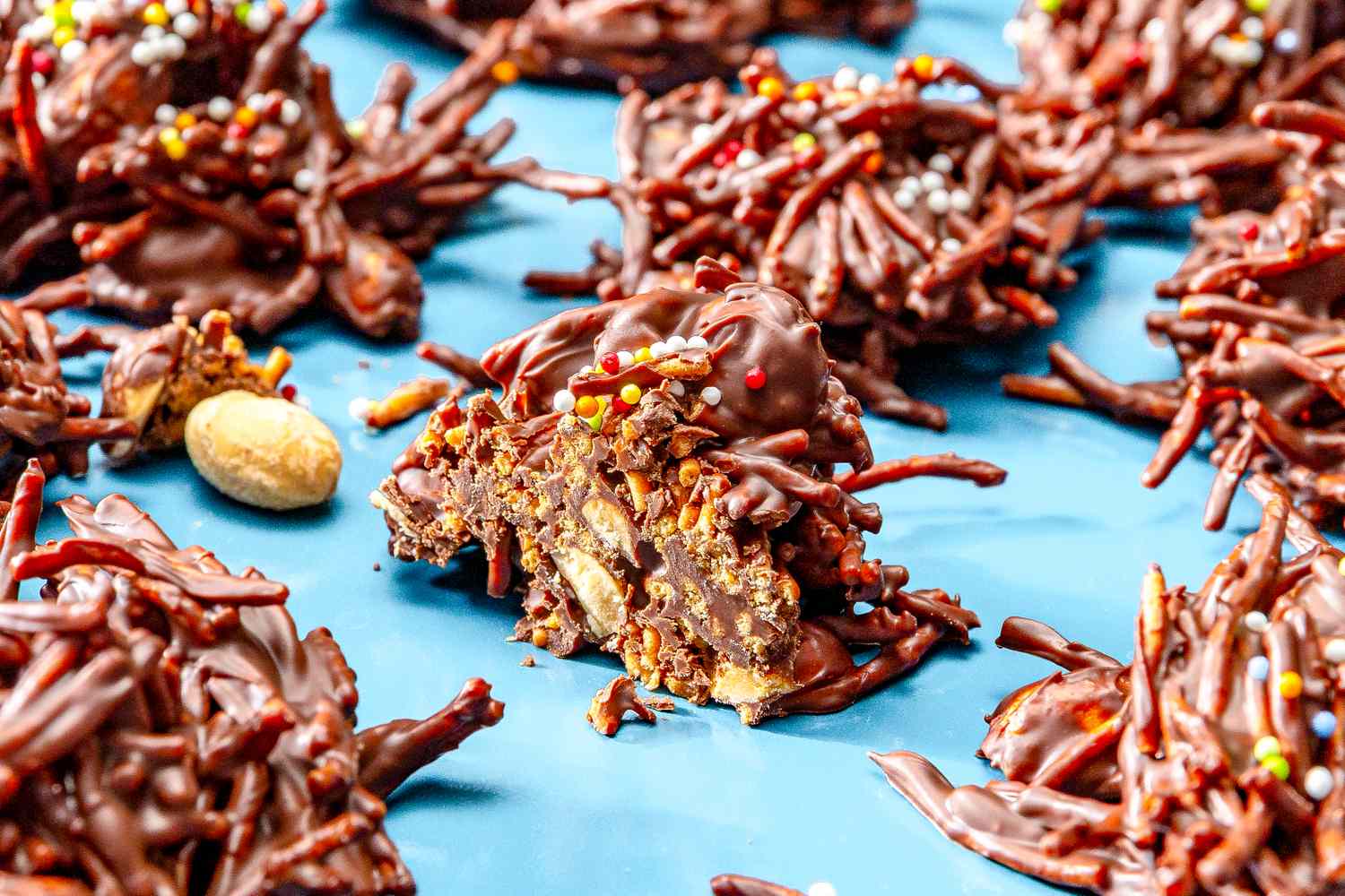 Chocolate chow mein cookies topped with sprinkles on a blue surface
