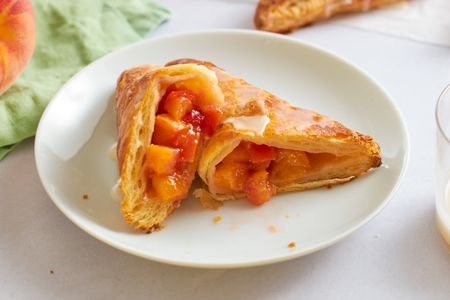Peachfilled turnover pastry cut open on a white plate