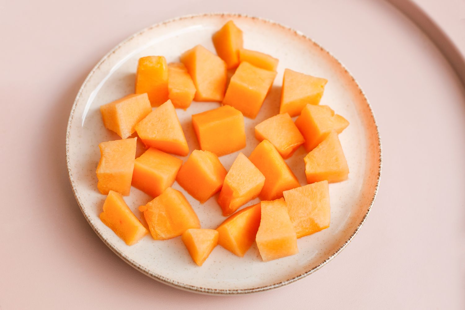 Diced pieces of cantaloupe on a white plate
