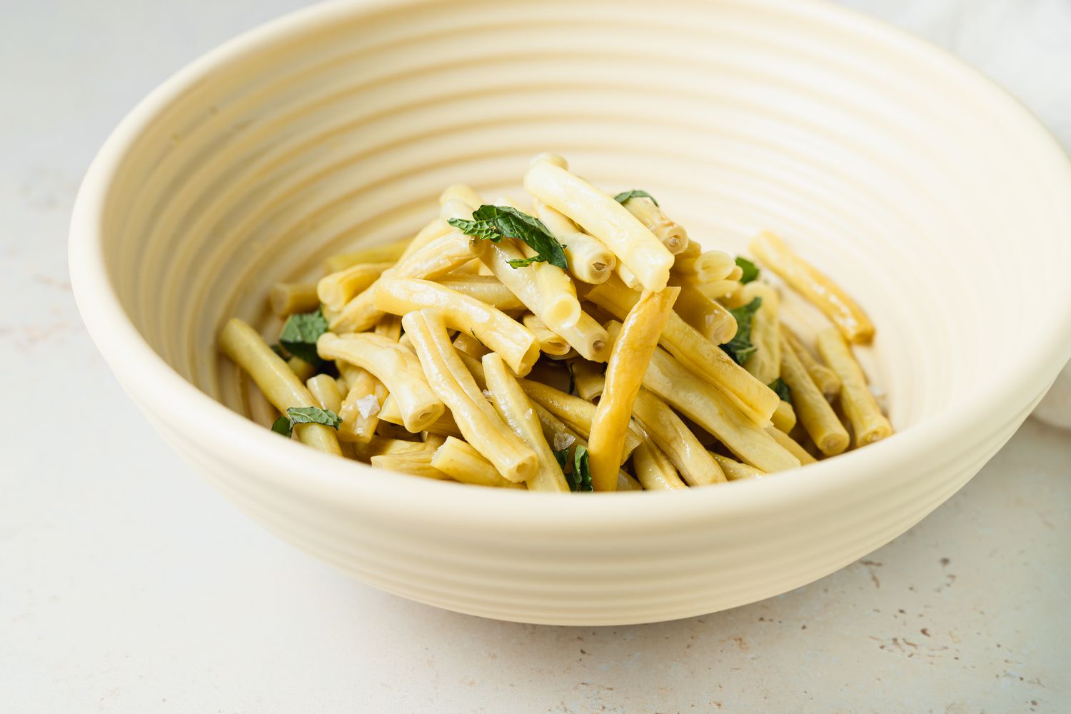 Side view of yellow beans in a cream colored bowl.