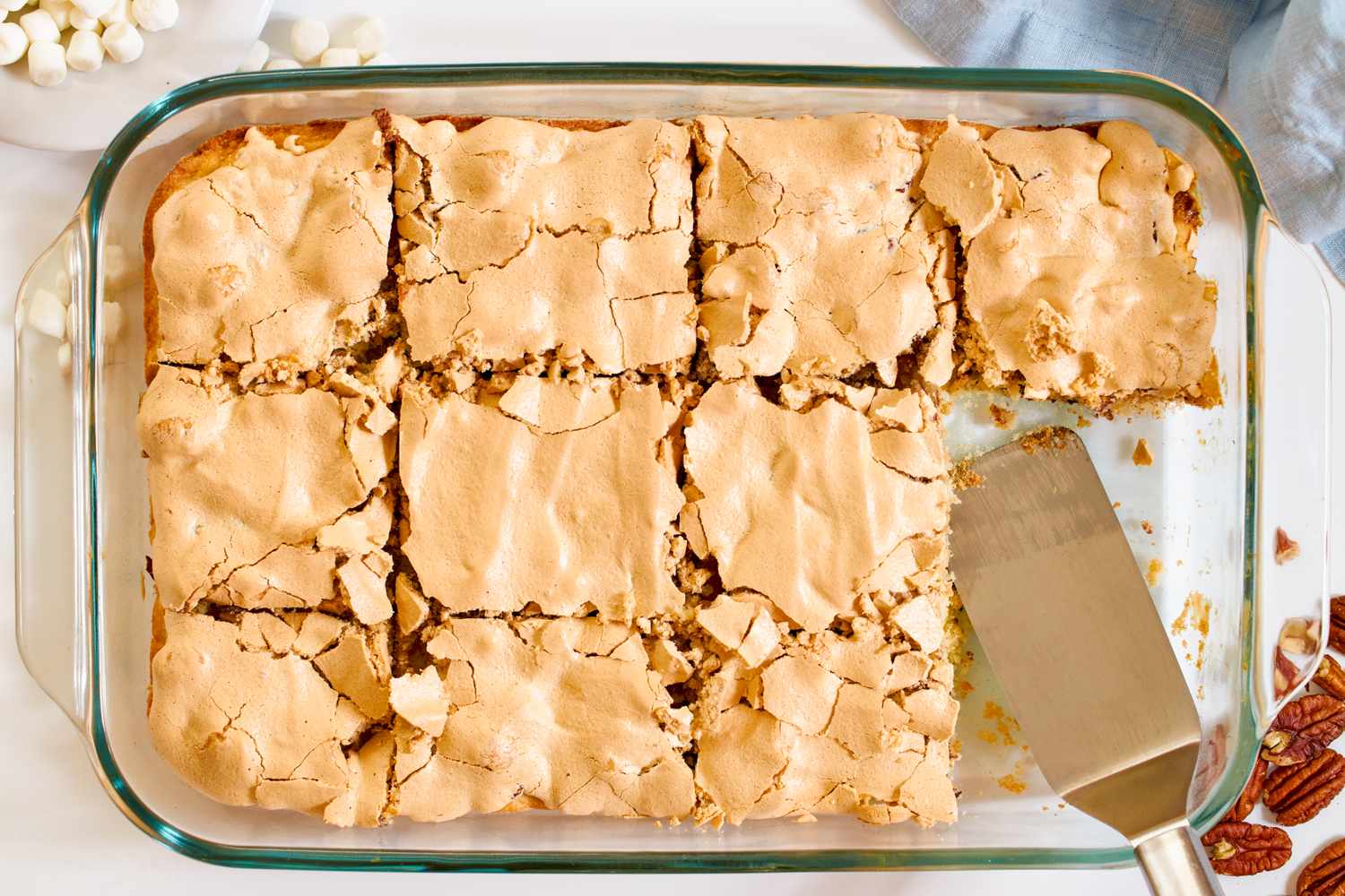 Rectangular glass baking dish with meringue topped cookie dough cut into squares for mud hen bars recipe