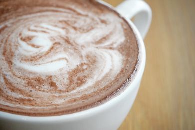 A cup of hot chocolate with a swirled design on the surface