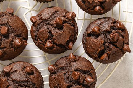 Chocolate muffins topped with chocolate chips cooling on a wire rack