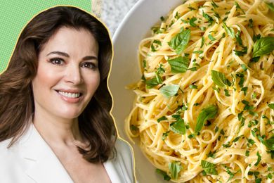 Nigella Lawson next to a plate of lemon linguine garnished with herbs.