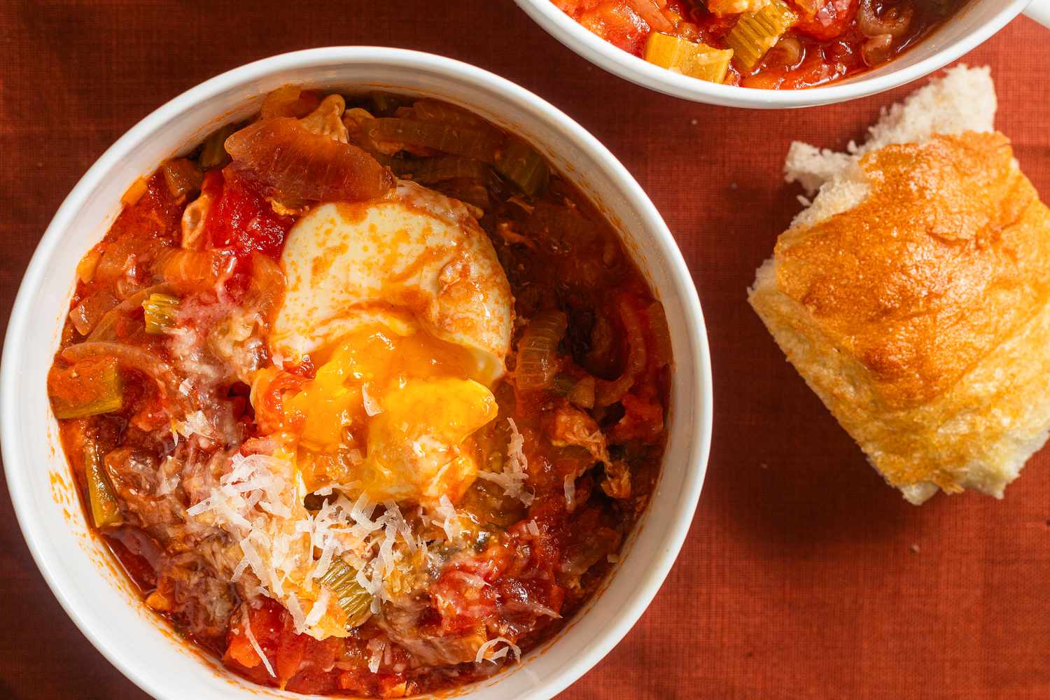 Overhead view of Tuscan Soup in a white bowl with a piece of bread to the side