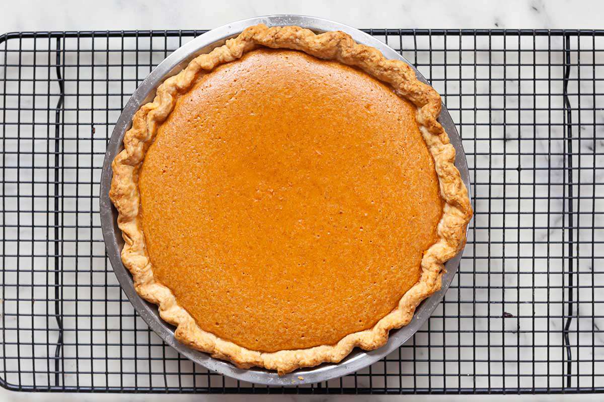 Whole classic sweet potato pie on a baking rack to cool.