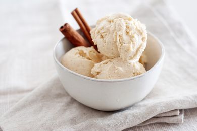 A bowl of cinnamon ice cream with two cinnamon sticks in the bowl.