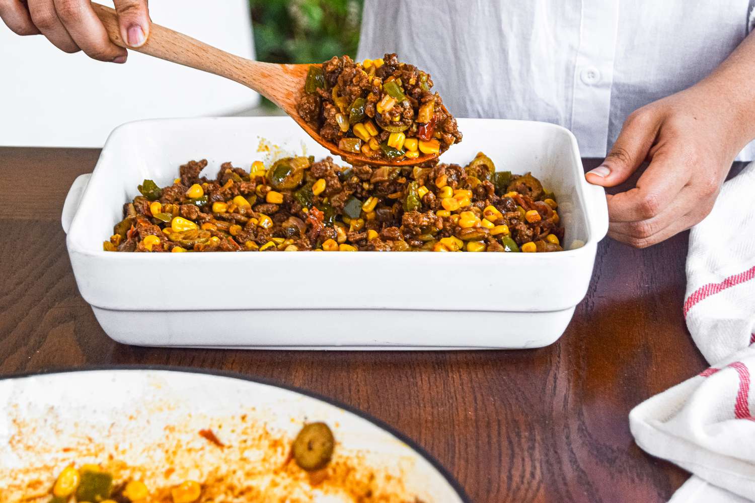 Spooning the filling for a tamale pie recipe in a casserole dish.