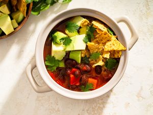 Bowl of tortilla soup with avocados chips and cilantro garnishes