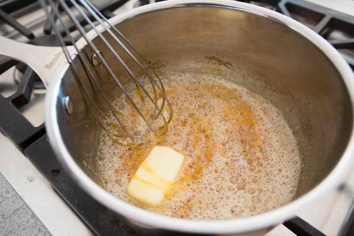 Boiling caramel sauce with butter cube and whisk