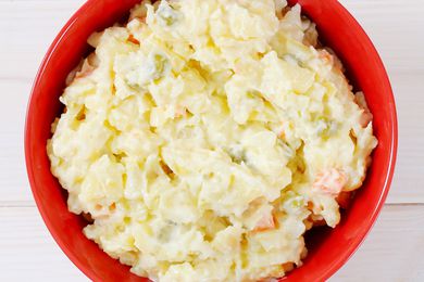 Overhead shot of a red bowl of creamy looking potato salad