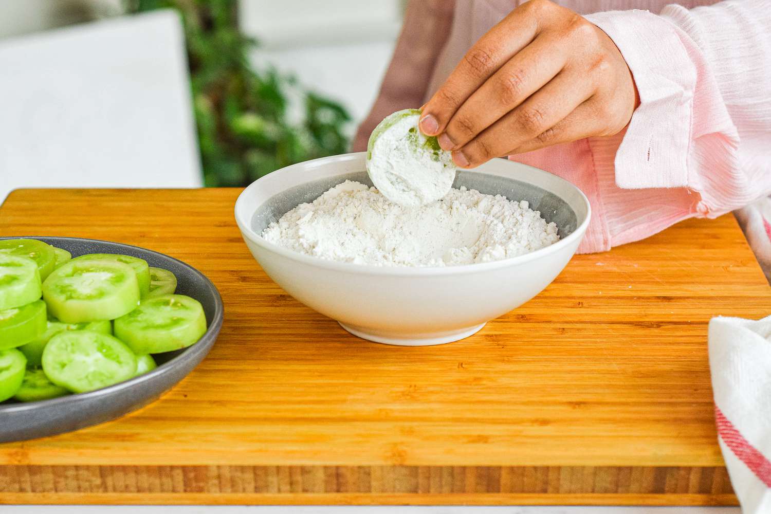 Dipping green tomatoes in flour mixture.