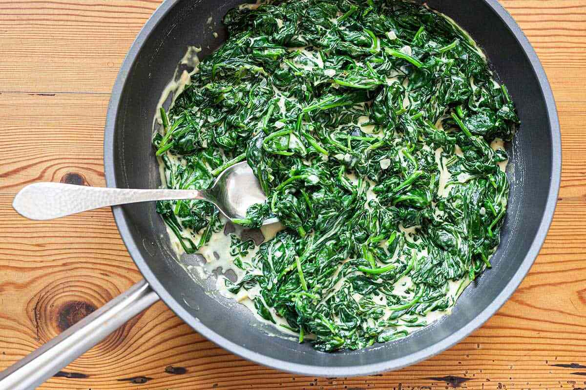 A saucepan with the Best Creamed Spinach in a skillet.