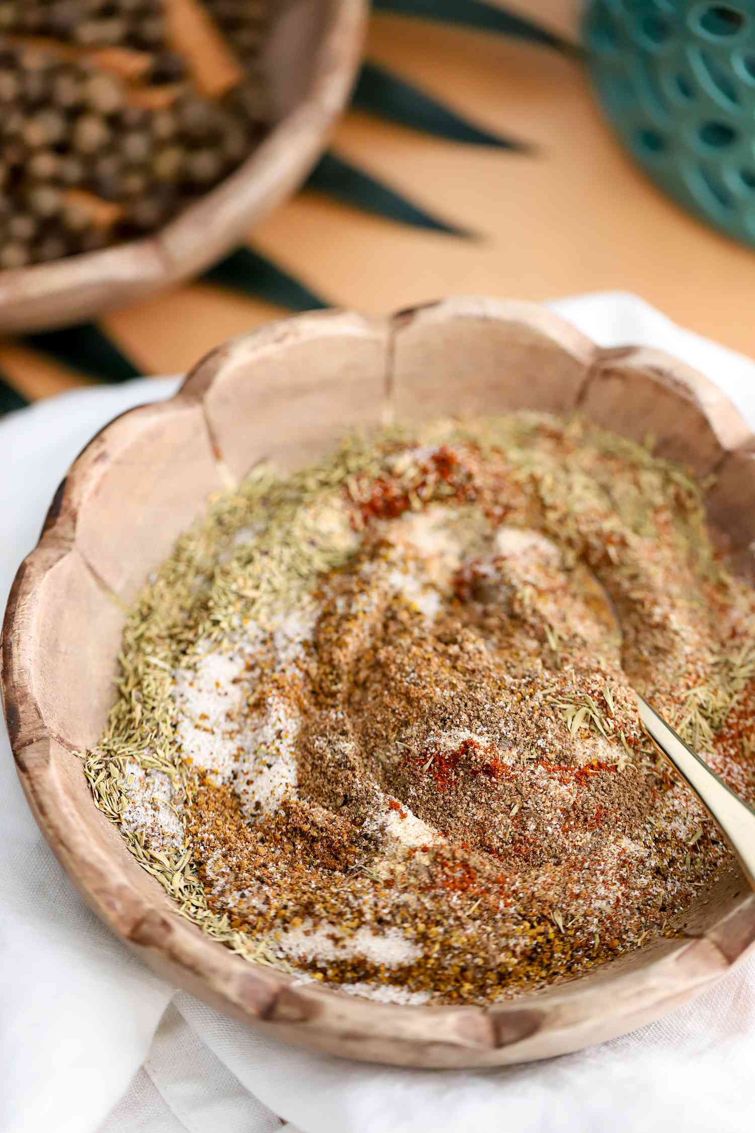 Bowl With Jerk Seasoning and a Spoon, Sitting on a Kitchen Towel and in the Background, a Bowl With Whole Allspice and Cinnamon Sticks