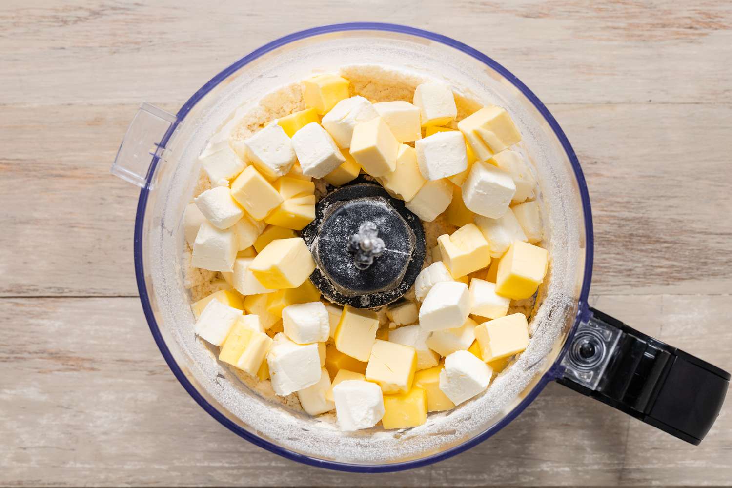 Cubed butter in a food processer with powdered sugar for pecan pie cookie recipe