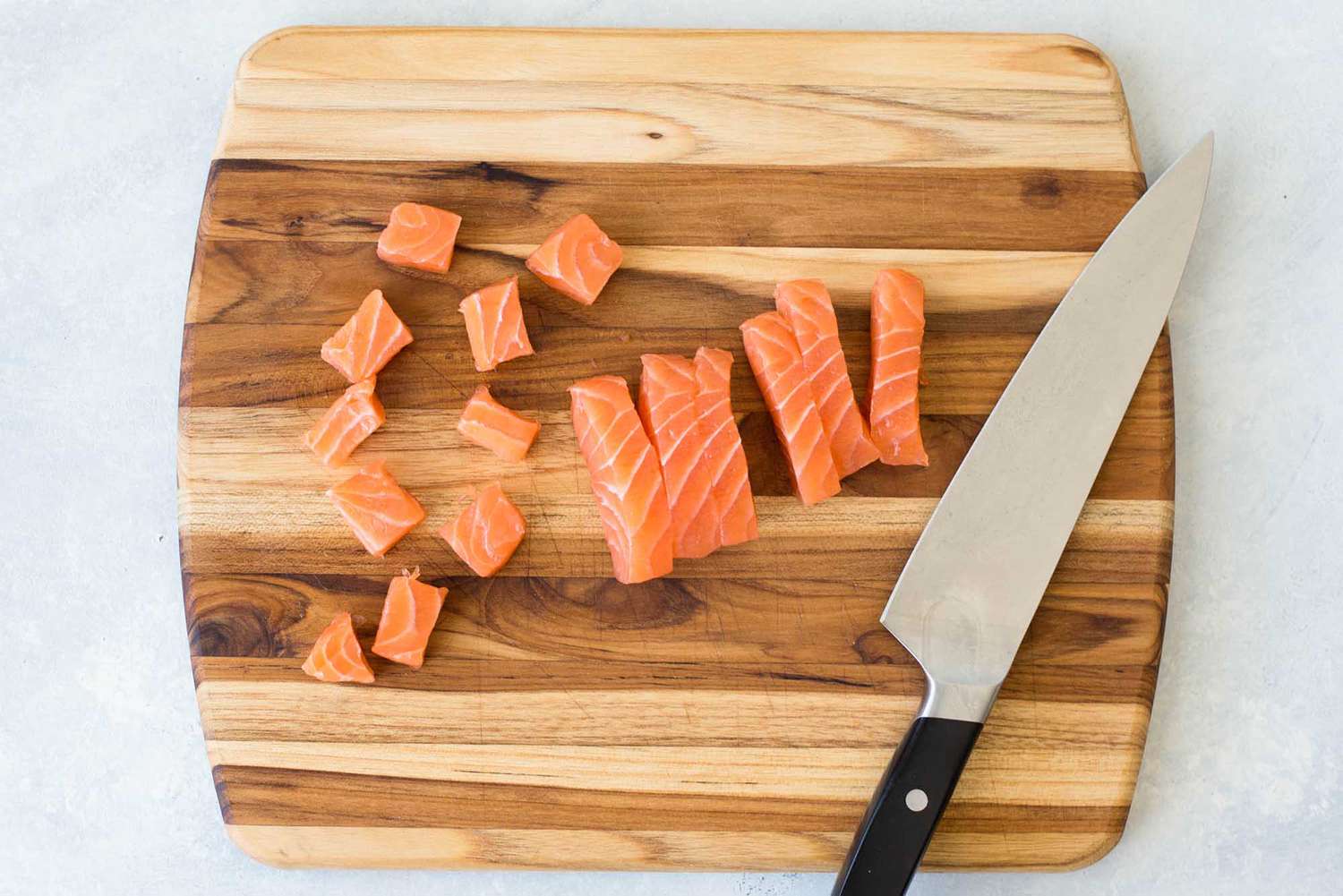 sliced salmon on wooden cutting board with knife