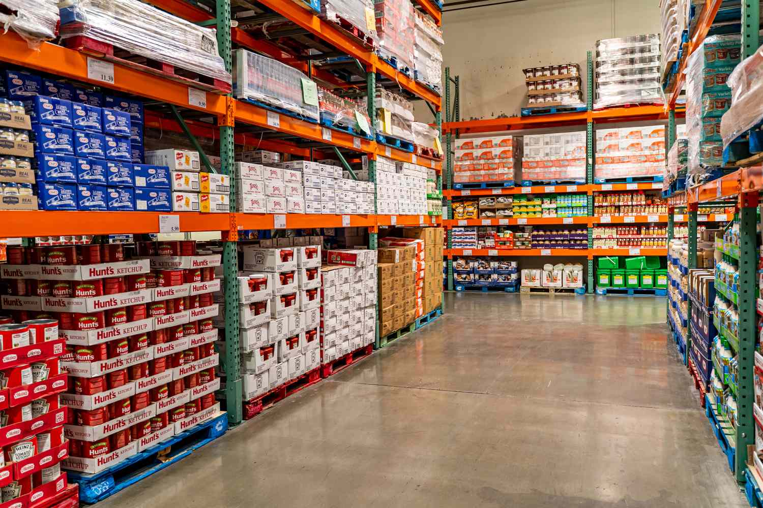 A stockroom aisle in a warehouse with shelves containing various boxed and packaged goods displayed