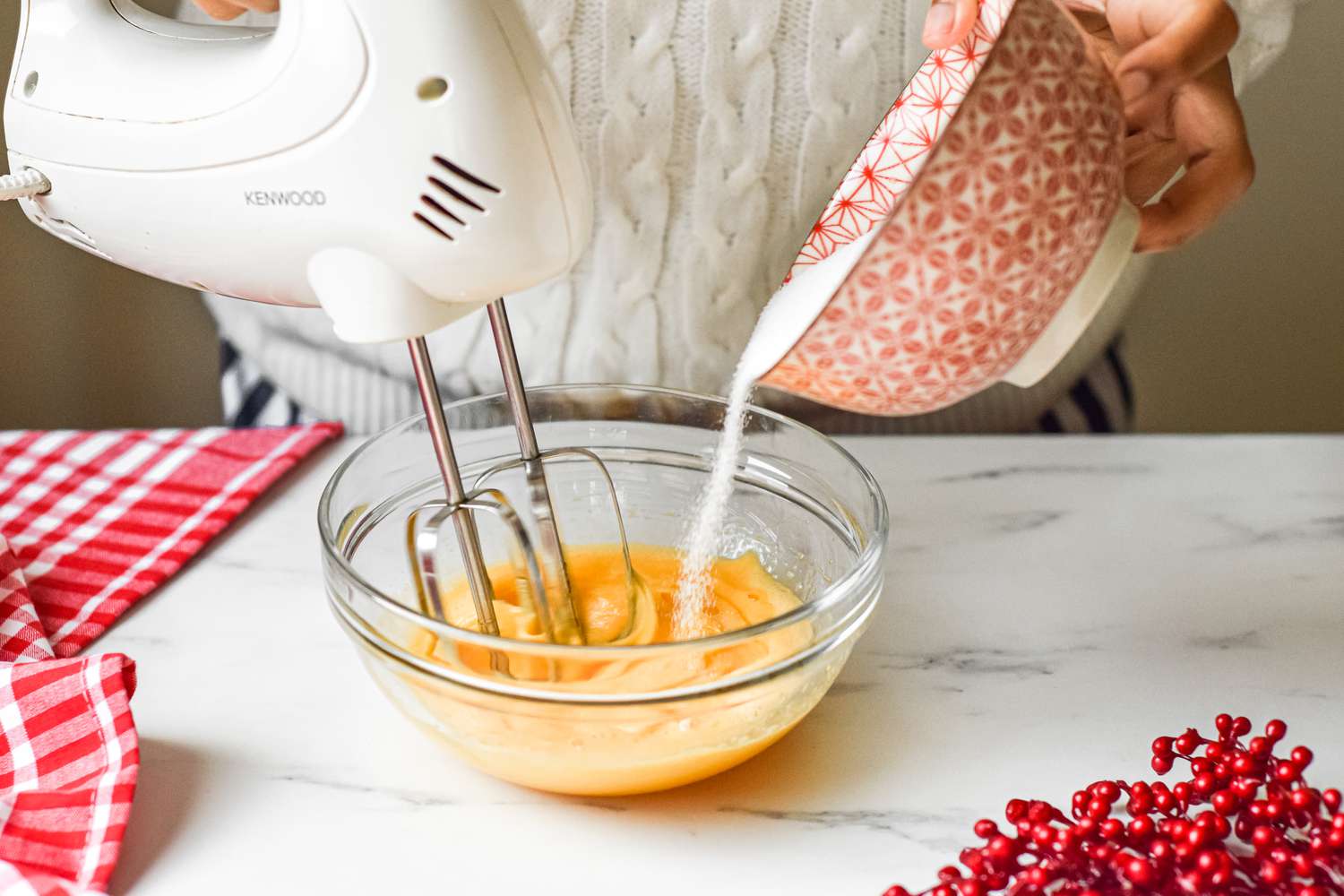 Making an eggnog recipe with a hand mixer and a glass bowl.