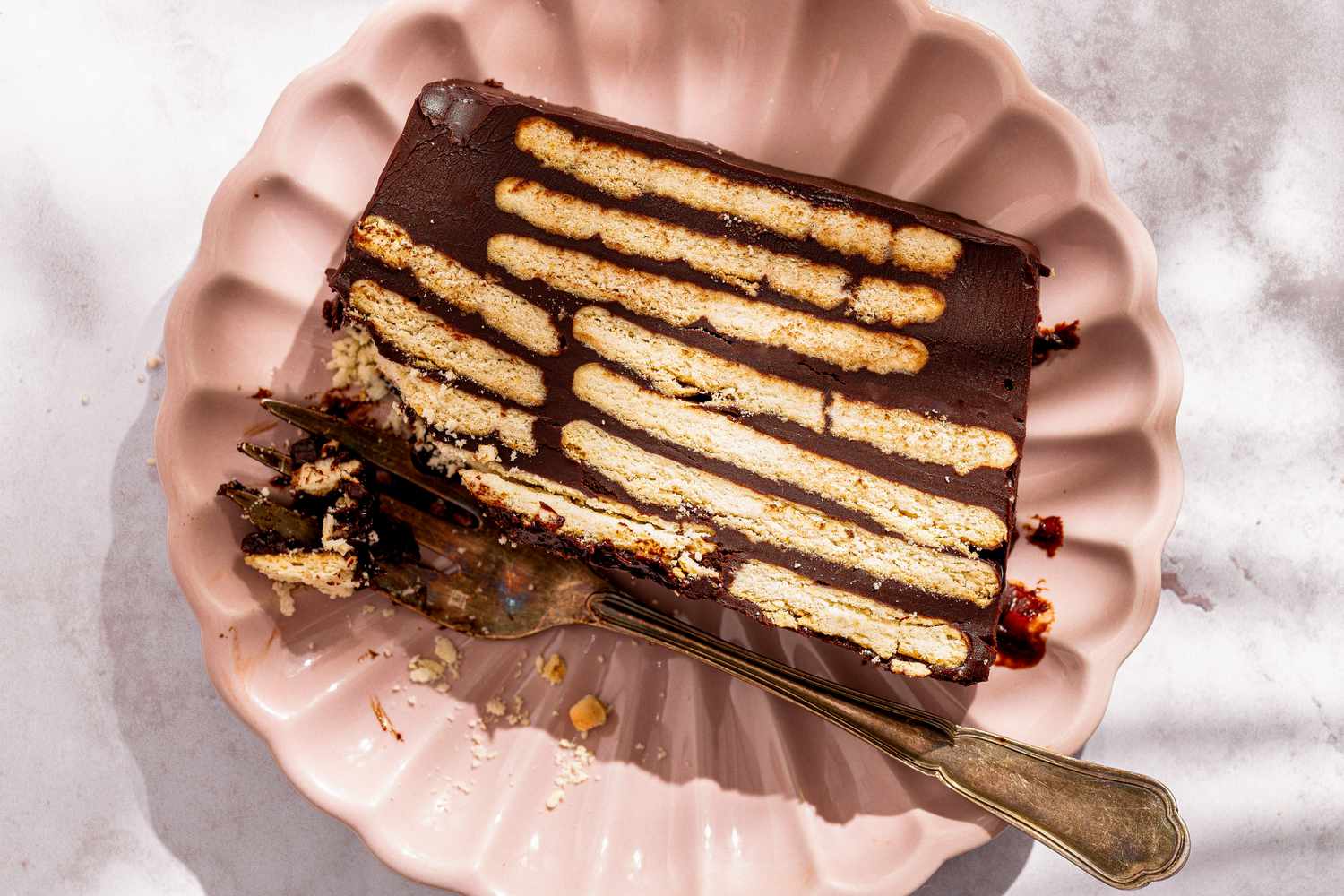 A slice of chocolate biscuit cake on a plate with a fork