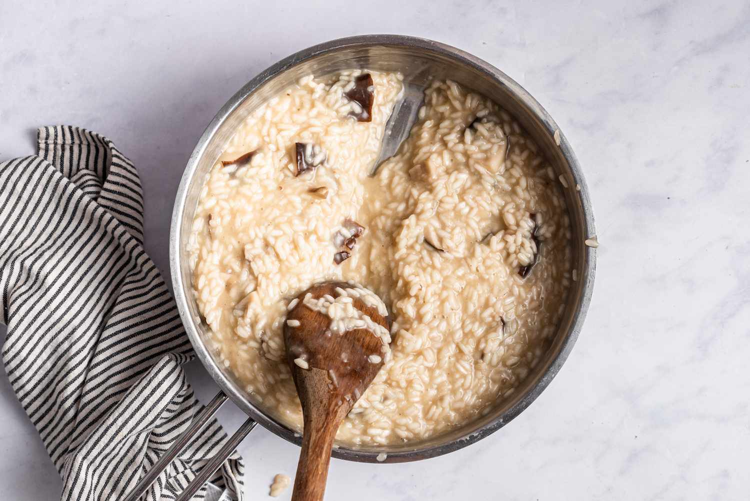 A wooden spoon stirring a creamy risotto in a pot