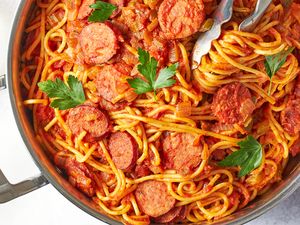 Spaghetti in tomato sauce with sausage slices in a pan