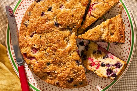 berry buckle (some of cut into slices) on a plate at a cozy table setting (cottagecore vibes)