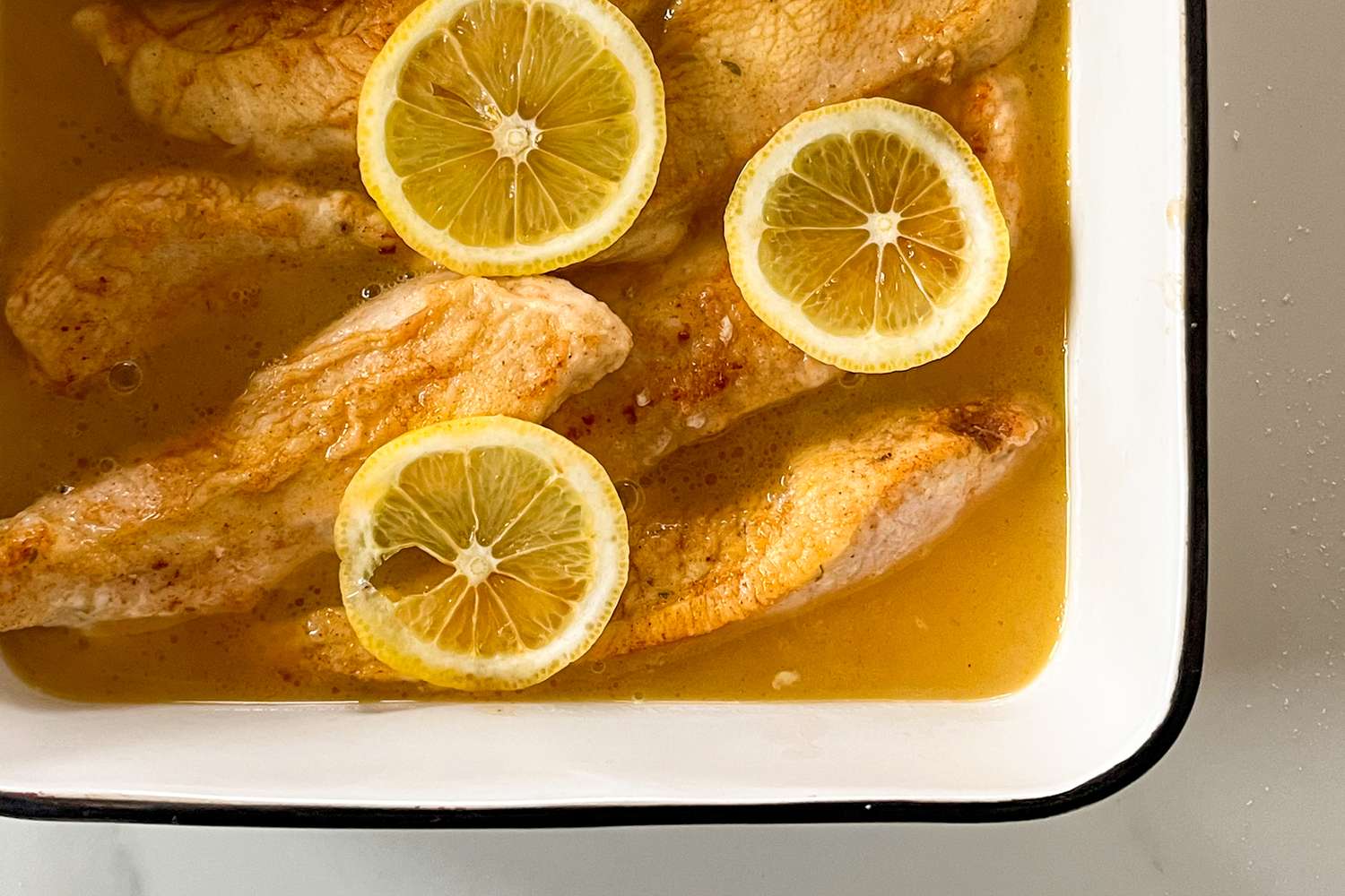 Cooked chicken pieces in a dish garnished with lemon slices