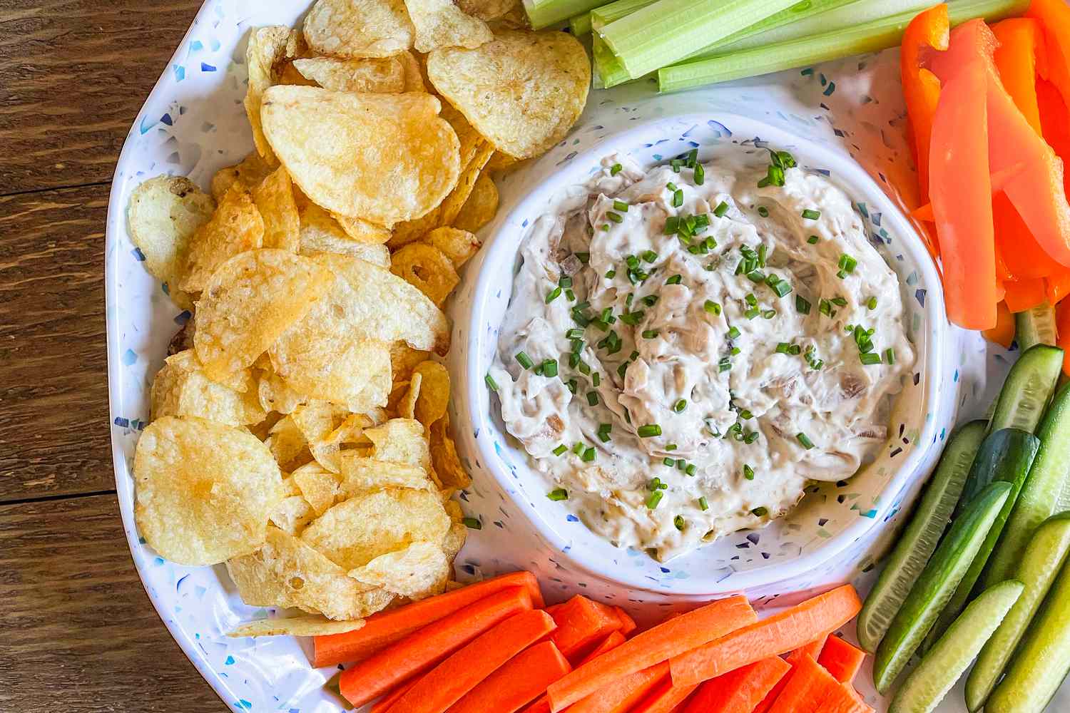 Overhead shot of a bowl of Ina Garten's pan fried onion dip surrounded by crudité