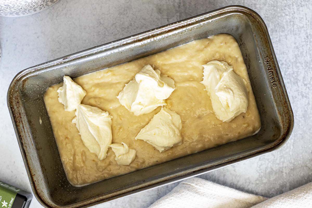 Easy cream cheese banana bread batter in a pan with dollops of cream cheese on top.