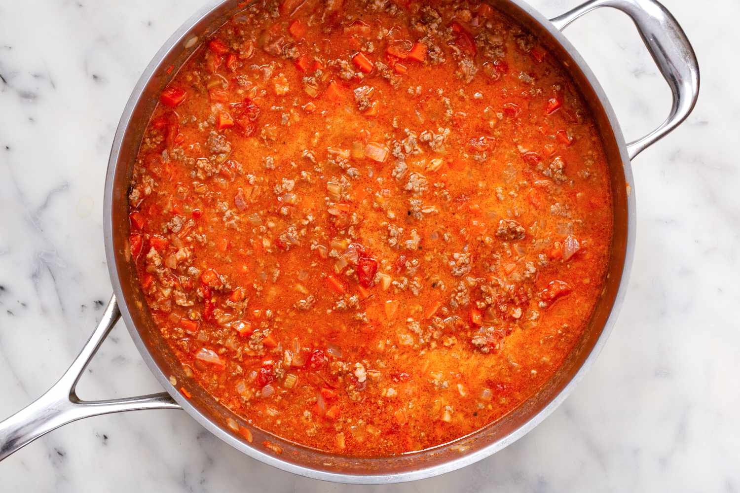 A skillet with bolognese sauce simmering inside.
